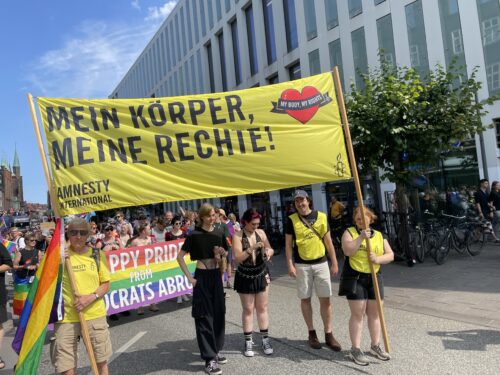Mitglieder der Amnesty Gruppe Lübeck mit dem Banner "Mein Körper, meine Rechte!" beim CSD in Lübeck
